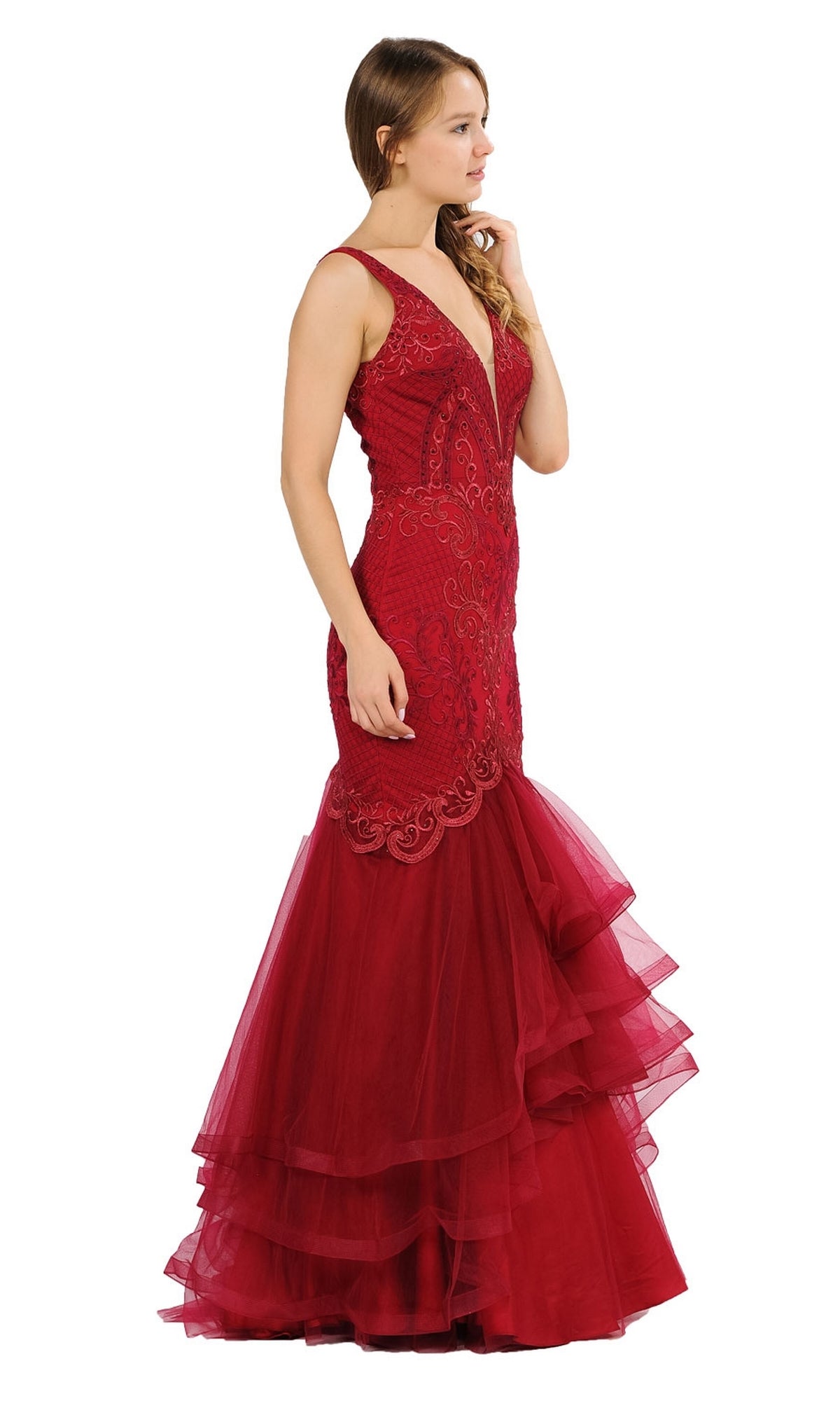 A woman in profile wears the Embroidered V-Neck Mermaid Formal Prom Dress 8320, a sleeveless deep red gown with embroidery, a deep V-neckline, and layered tulle skirt, standing against a white background.